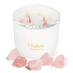 the chakra rose quartz candle is next to some pink crystal chunks on a white surface