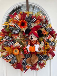 a mickey mouse wreath on the front door with fall leaves, pumpkins and sunflowers