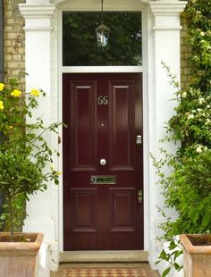 a red front door with two planters on either side