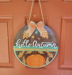 a wooden sign hanging from the side of a door with an orange pumpkin on it