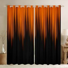 an orange and black curtain hanging in front of a white wall with a lamp on it