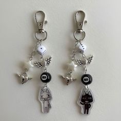 two keychains with charms attached to them on a white surface, one has a cat and the other is a dog