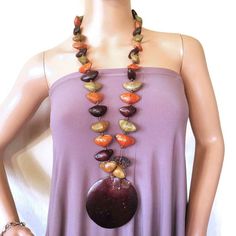 Vintage long women's necklace with coconut shell pendant. Made of natural palm seeds in brown, orange and green colors. Total length 36''/92cm without pendant pendant  -3.5''/9cm diameter Good vintage condition with minor wear.