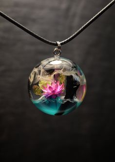 a glass ball with flowers in it hanging from a string on a black background,