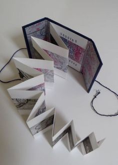 an open book sitting on top of a white table next to a string and scissors