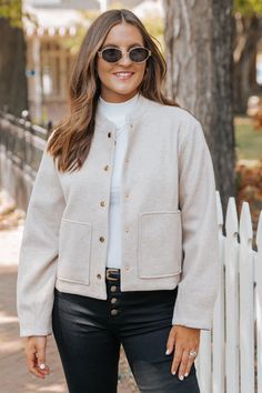 Be effortlessly stylish with this Bomber Jacket in Beige! The long sleeves and elastic back hem provide a comfortable fit, while the gold button detail adds a touch of elegance. With a snap button closure and side pockets, this jacket is as functional as it is fashionable. Lined for added warmth. Layer it over a basic tank top or bodysuit and then pair with jeans, ankle booties, and a matching crossbody bag for an elevated boho chic look! Versatile Fall Outerwear With Buttons, Versatile Winter Outerwear With Buttons, Versatile Button-up Fall Outerwear, Versatile Spring Outerwear With Buttons, Versatile Long Sleeve Outerwear For Day Out, Versatile Fall Blazer With Button Closure, Classic Button-up Outerwear For Day Out, Chic Button-up Everyday Outerwear, Fall Cropped Jacket With Buttoned Pockets And Long Sleeves