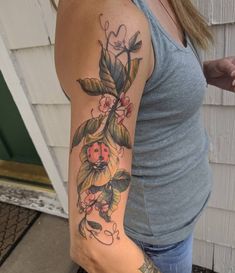 a woman with a flower tattoo on her arm and shoulder is standing in front of a house