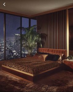 a bedroom with a leopard print comforter and large windows overlooking the city at night