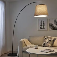 a living room with a couch, coffee table and floor lamp in the corner next to a window