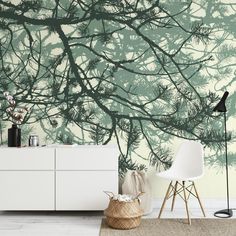 a living room with a white dresser and wallpaper that has green trees on it