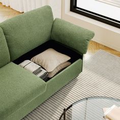 a living room with a green couch and glass coffee table in front of a window