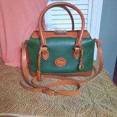 Dooney & Bourke Green Doctor Bag All Weather Leather Handbag **Priority shipping available at checkout**  This sought after vintage beauty in highly desired green and tan has a classic style with room for all of your favorite things! Comes with it's original key for working closure lock!  Part of Dooney & Bourke's wonderful line of All Weather Leather bags that are  designed to last.  This bag is wonderfully constructed and has aged beautifully for a great vintage look. Bag features:  All Weather green pebbled leather with British tan trim. Brass hardware. Leather carry handles. Long strap for shoulder/crossbody carry. Top closure has two flaps that meet with brass latch closure (bag can be locked with included key). Hanging clochette houses key. Brass Dooney & Bourke duck fob. Interior re Retro Green Bag With Removable Pouch, Retro Green Satchel Shoulder Bag, Retro Green Shoulder Bag Satchel, Retro Green Shoulder Satchel, Vintage Green Satchel With Double Handle, Green Vintage Satchel With Double Handle, Retro Green Crossbody Satchel, Vintage Green Double Handle Satchel, Retro Green Tote Bag