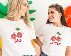 two women wearing matching shirts with cherries on them