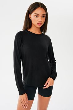 Front shot of woman with dark straight hair, wearing black sweatshirt with black shorts Black Relaxed Fit Tops With Thumbholes, Black Crew Neck Activewear For Layering, Black Everyday Activewear For Fall, Black Tops With Ribbed Cuffs, Fall Crew Neck Versatile Activewear, Versatile Crew Neck Activewear For Fall, Versatile Fall Activewear Crew Neck, Versatile Crew Neck Fall Activewear, Versatile Crew Neck Tops With Ribbed Cuffs