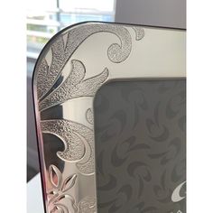 an ornate silver and pink photo frame sitting on top of a white table next to a window