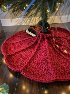 a red knitted bag sitting on top of a wooden floor next to a christmas tree