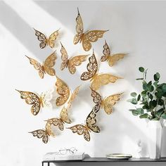 a white table with a vase and some gold butterflies on it's side wall