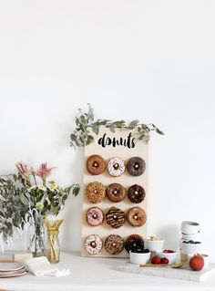 a wooden sign with doughnuts on it next to flowers and other food items