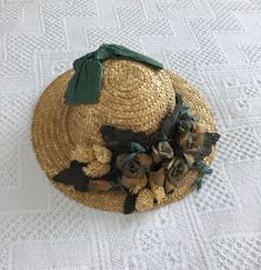 a straw hat with flowers on it sitting on a white tablecloth covered flooring