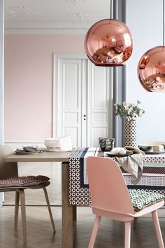 a dining room table with two chairs and a pink ball hanging from the ceiling over it