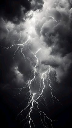 a black and white photo of lightning striking through the dark cloudy sky, taken from ground level