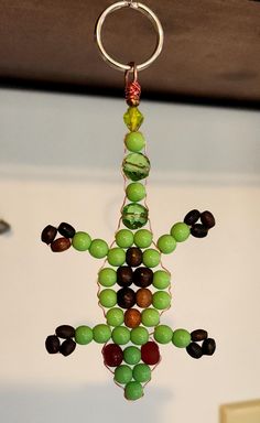 a wind chime hanging from the ceiling with beads on it's sides and a ring around its neck