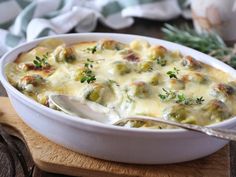 a casserole dish with broccoli and cheese in it on a cutting board