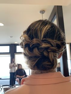 the back of a woman's head with braids in her hair and people standing around