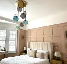 a bed room with a neatly made bed and two lamps hanging from the headboard