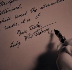 a person writing on a piece of paper with a fountain pen in their left hand