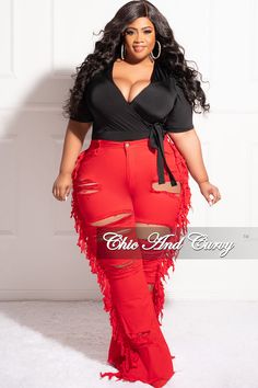 a woman in red pants and black top posing for the camera with her hands on her hips