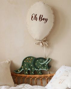 a balloon shaped like a dinosaur is on the wall next to a bed with pillows