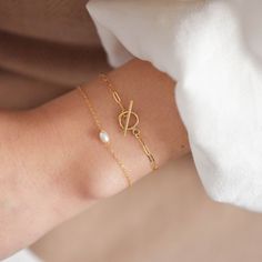 "This bracelet features a small toggle closure on a dainty paperclip gold chain that measure 2 mm wide and can be made to fit your wrist snugly. Toggle measures 9mm wide. Be sure to measure your wrist if you are going for a tight fit like the model who is wearing the 5.75 inches. Otherwise, the standard length at department stores for women's bracelets is 7 inches. This item is 14k gold filled and is tarnish-resistant, water-resistant, and hypoallergenic. --------------------♥ PROMOS ♥---------- Gold Oval Link Oyster Bracelet Gift, Classic Oval Link Bracelets As Gift, Timeless Oval Link Gold Bracelet As Gift, Timeless Paperclip Bracelet For Gift, Timeless Adjustable Chain Bracelet With Oyster Detail, Elegant Sterling Silver Bracelet With Clasp For Gift, Modern Yellow Gold Pearl Bracelet As Gift, Modern Yellow Gold Pearl Bracelet For Gift, Modern Yellow Gold Pearl Bracelet Gift