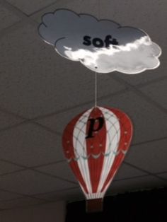 a red and white hot air balloon with the word soft hanging from it's side