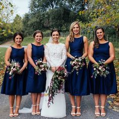 a group of women standing next to each other in front of trees and leaves on the ground