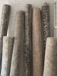 a bunch of rugs lined up against a brick wall in a room with white bricks