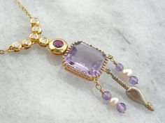 We crafted this one of a kind, unique necklace using pieces from a variety of eras! The center piece is an exquisite amethyst pendant that comes from the Art Nouveau era. We've added pearl and amethyst beads strung on gold wire, and an antique Victorian pendant to the base of this neat piece! The necklace we've chosen to finish this with is contemporary, with bezel set diamonds and a fine, deep red ruby at the center.Metal: 18k Yellow GoldGemstone: Amethyst Gem Measurements: 13.4 x 12.1 mm, Rect Luxury Amethyst Necklace For Formal Occasions, Exquisite Amethyst Necklace For Formal Occasions, Luxury Purple Pendant Necklace, Exquisite Formal Amethyst Necklace, Luxury Yellow Gold Amethyst Necklace, Luxury Purple Necklaces For Anniversary, Luxury Purple Necklace For Anniversary, Luxury Multi-stone Amethyst Necklace, Luxury Amethyst Multi-stone Necklace