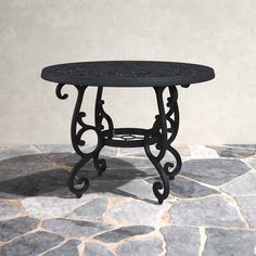 an iron table sitting on top of a stone floor