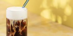 a glass filled with liquid sitting on top of a counter next to a yellow wall