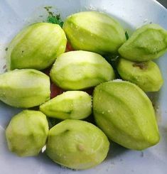 a white bowl filled with green fruit sitting on top of a table