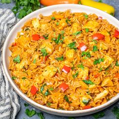 a white bowl filled with rice and vegetables on top of a blue table cloth next to peppers