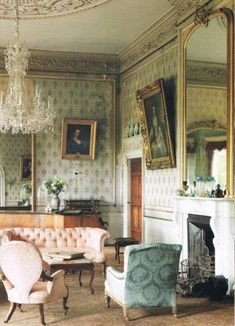 a living room filled with lots of furniture and a chandelier hanging from the ceiling