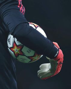 a person holding a soccer ball in their right hand and wearing gloves on the other