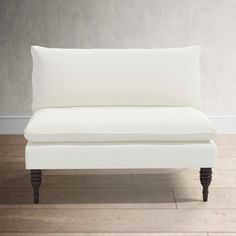 a white couch sitting on top of a hard wood floor next to a gray wall