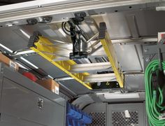 the inside of a vehicle with metal shelves and yellow ladders hanging from it's ceiling