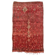 an old red rug with fringes on the bottom and sides, in different colors