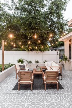 an instagram photo of a patio with lights strung above the dining table and chairs