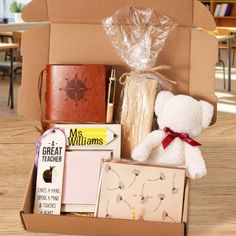 a teddy bear sitting inside of a box filled with books and other items on a table