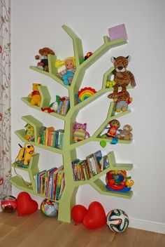 there is a tree that has many books on it and toys in the bottom shelf