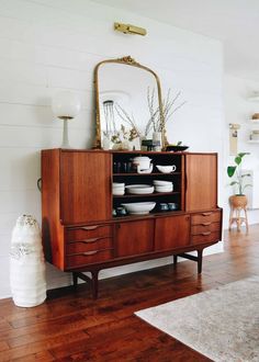 a wooden cabinet sitting on top of a hard wood floor next to a white wall